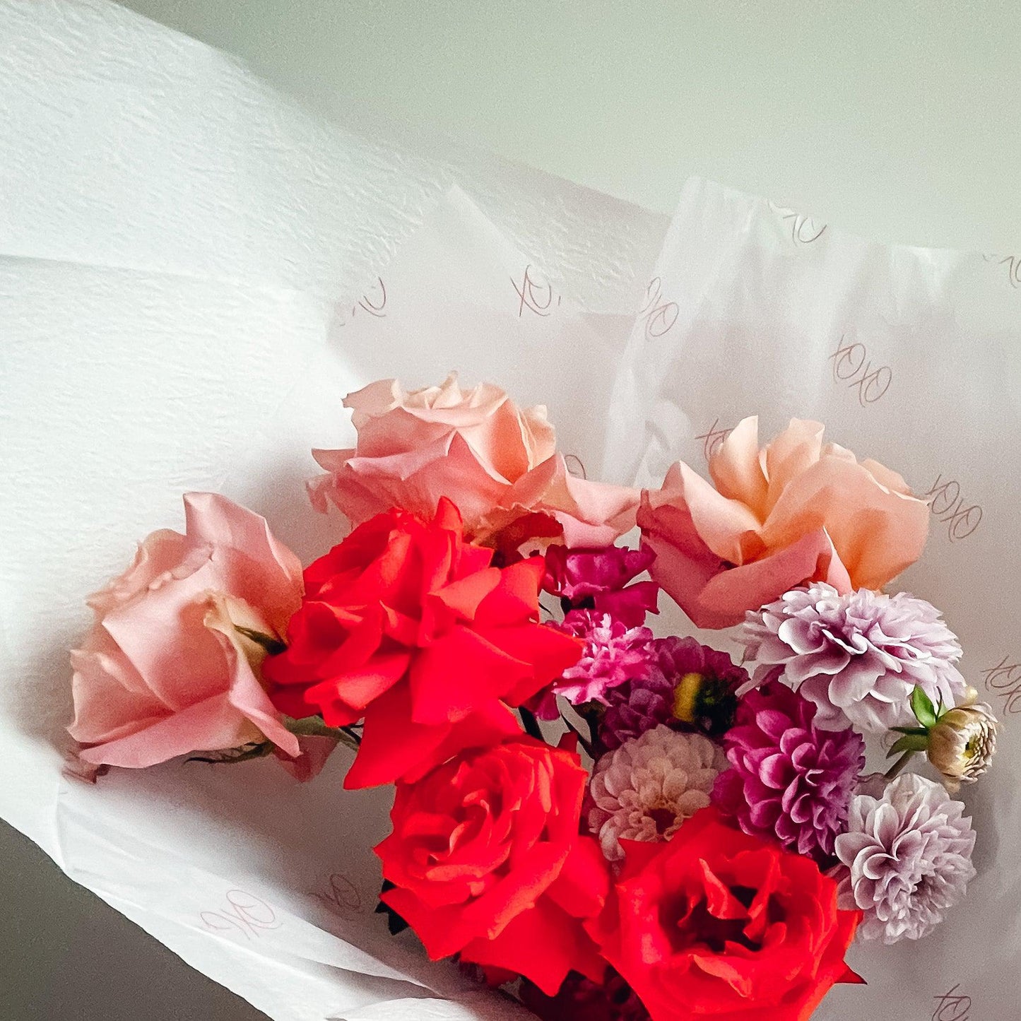 Bright flowers in pink, red and purple, made into a bouquet and wrapped in white paper